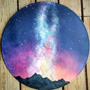 Skyscape with mountains in silhouette painted onto a record player.