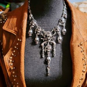 Photograph of a metal necklace decorated with skulls and chains